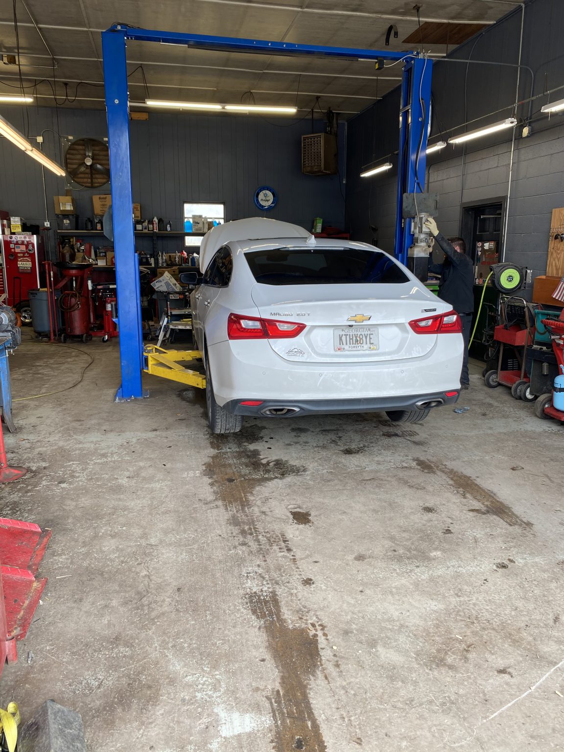 A car up on the lift at Total Automotive while a mechanic works